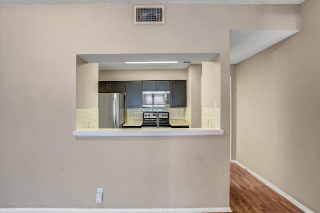 807 W 25th St Unit 307, Austin, TX 78705 - kitchen featuring appliances with stainless steel finishes, tasteful backsplash, wood finished floors, and light countertops