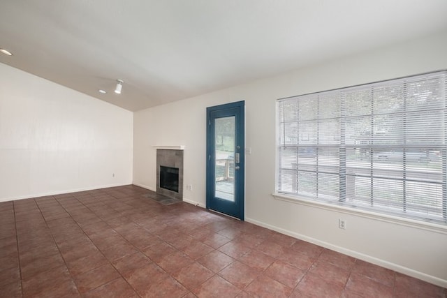 1102-1104-1106 Academy St, San Marcos, TX 78666 - unfurnished living room featuring a tiled fireplace, lofted ceiling, baseboards, and tile patterned flooring