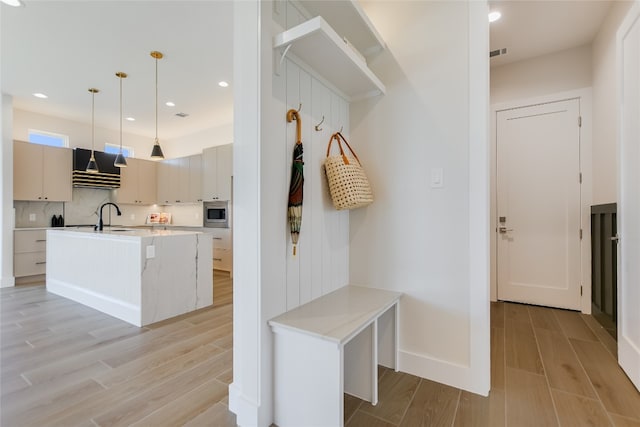 1603 Sapphire, Horseshoe Bay, TX 78657 - mudroom featuring recessed lighting, baseboards, a sink, visible vents, and light wood-style flooring