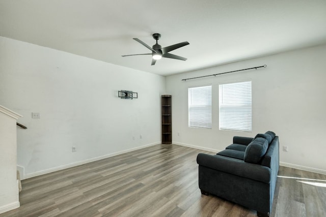 living area with baseboards, wood finished floors, and a ceiling fan