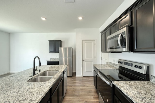 kitchen featuring a sink, stainless steel appliances, light stone counters, and dark wood-style flooring