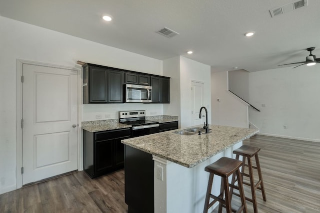 kitchen featuring a sink, a center island with sink, visible vents, and stainless steel appliances