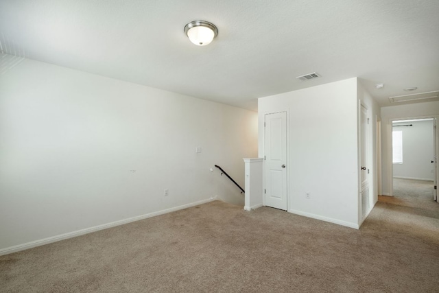 spare room with light colored carpet, visible vents, and baseboards