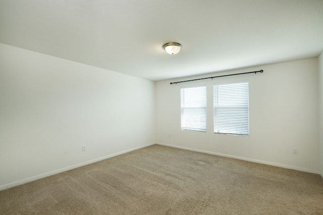 empty room featuring light carpet and baseboards