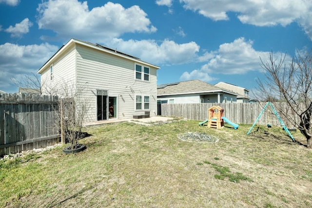 rear view of property featuring a patio, solar panels, a fenced backyard, a playground, and a lawn