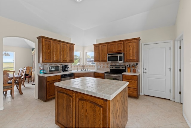 341 Brown Rd, Mcdade, TX 78650 - kitchen featuring a kitchen island, arched walkways, a sink, stainless steel appliances, and backsplash