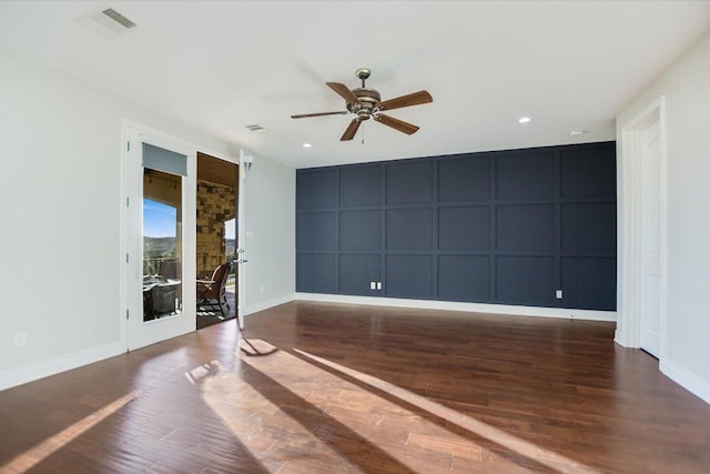 spare room with wood finished floors, recessed lighting, a decorative wall, baseboards, and ceiling fan