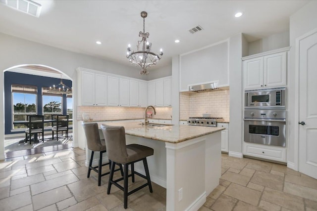 211 Jack Nicklaus Dr, Austin, TX 78738 - kitchen featuring appliances with stainless steel finishes, a chandelier, tasteful backsplash, recessed lighting, and stone tile flooring