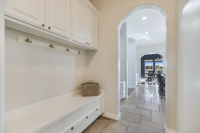 mudroom featuring visible vents, baseboards, stone tile floors, recessed lighting, and arched walkways