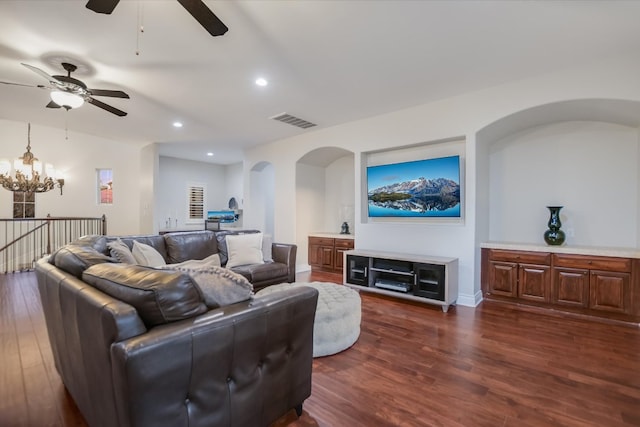 living room with visible vents, ceiling fan with notable chandelier, dark wood finished floors, recessed lighting, and arched walkways