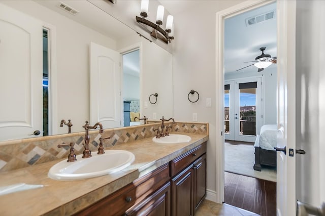 211 Jack Nicklaus Dr, Austin, TX 78738 - bathroom with double vanity, connected bathroom, french doors, a ceiling fan, and decorative backsplash