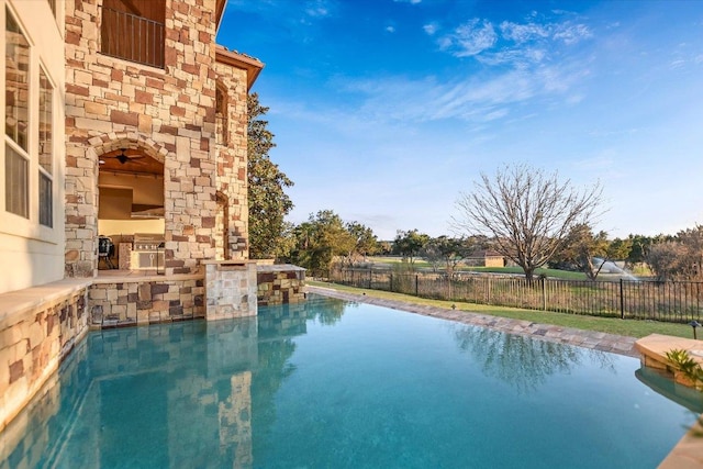 view of pool featuring a fenced backyard, a fenced in pool, and an outdoor kitchen