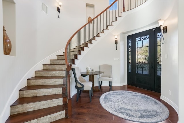 entrance foyer with visible vents, baseboards, stairway, a high ceiling, and wood finished floors