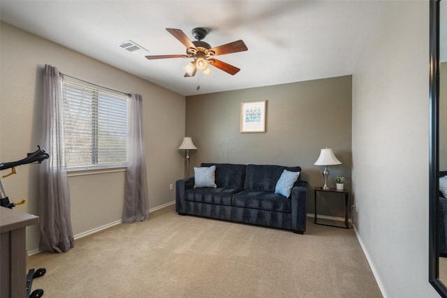 living area with visible vents, baseboards, light colored carpet, and ceiling fan