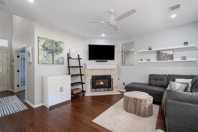 living room with visible vents, wood finished floors, baseboards, ceiling fan, and a tile fireplace