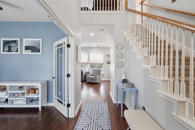 foyer entrance with stairs, baseboards, a high ceiling, and dark wood-style flooring