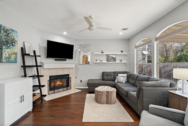 living area with a ceiling fan, a tile fireplace, dark wood-type flooring, and recessed lighting