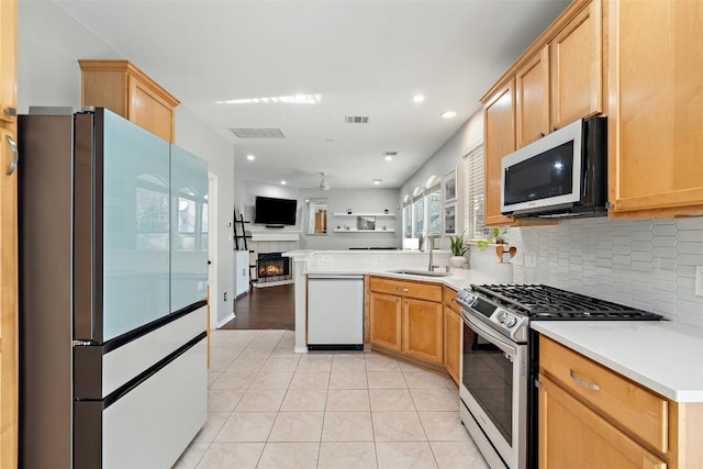 kitchen with white appliances, a sink, open floor plan, a fireplace, and tasteful backsplash