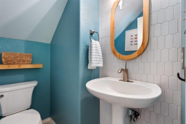 bathroom with lofted ceiling, toilet, and a sink