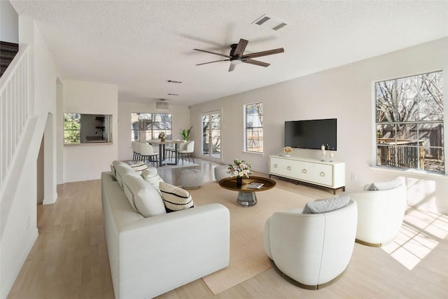 4320 Dos Cabezas Dr, Austin, TX 78749 - living room with a ceiling fan, a textured ceiling, light wood finished floors, and stairway