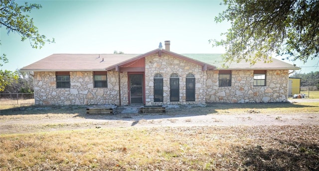 rear view of property with stone siding and fence