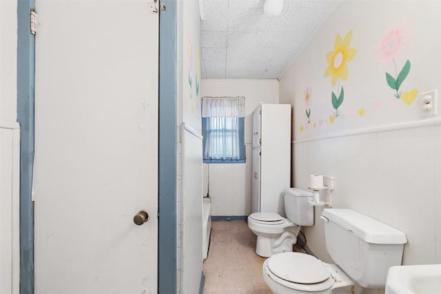 631 S Harris St, Giddings, TX 78942 - bathroom with a wainscoted wall, toilet, and a textured ceiling
