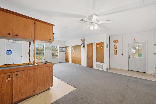 631 S Harris St, Giddings, TX 78942 - kitchen with light tile patterned floors, a ceiling fan, brown cabinetry, visible vents, and light carpet