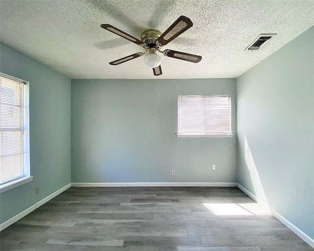 8602 Colonial Dr, Austin, TX 78758 - empty room with wood finished floors, a ceiling fan, healthy amount of natural light, and a textured ceiling