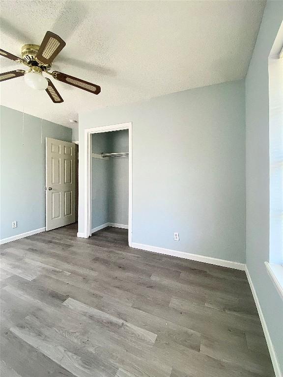8602 Colonial Dr, Austin, TX 78758 - unfurnished bedroom featuring wood finished floors, baseboards, a ceiling fan, and a textured ceiling