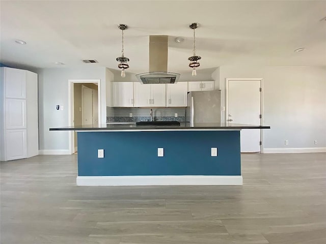 8602 Colonial Dr, Austin, TX 78758 - kitchen with freestanding refrigerator, dark countertops, island range hood, white cabinetry, and tasteful backsplash