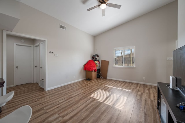 interior space featuring visible vents, wood finished floors, baseboards, ceiling fan, and vaulted ceiling