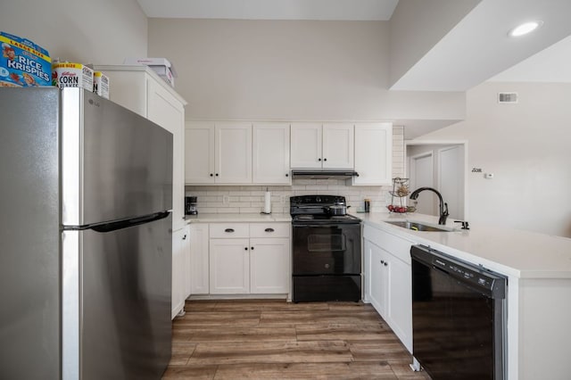 kitchen with visible vents, a peninsula, a sink, black appliances, and under cabinet range hood