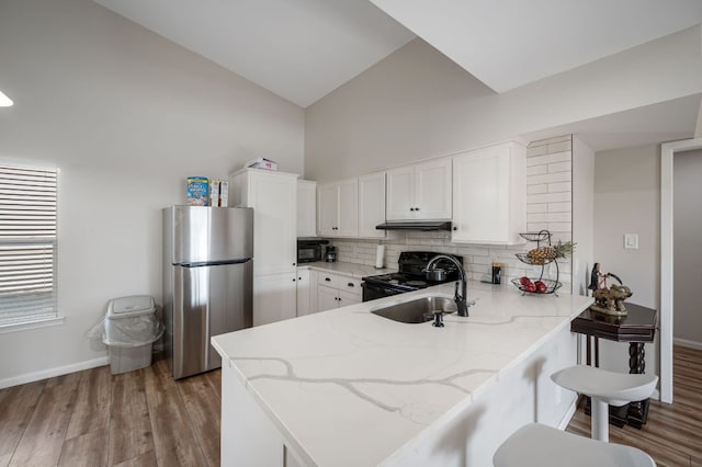 kitchen featuring backsplash, under cabinet range hood, a peninsula, black appliances, and a sink
