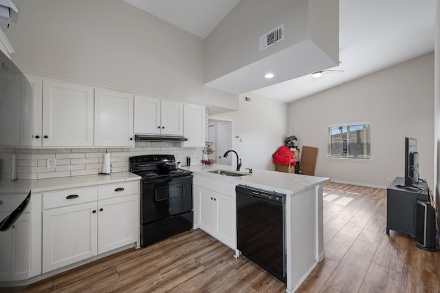 kitchen featuring visible vents, black appliances, a sink, under cabinet range hood, and a peninsula