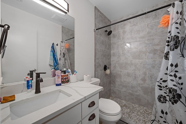 full bath featuring vanity, toilet, and tiled shower