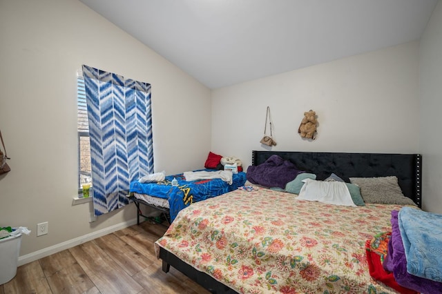 bedroom featuring baseboards, wood finished floors, and vaulted ceiling