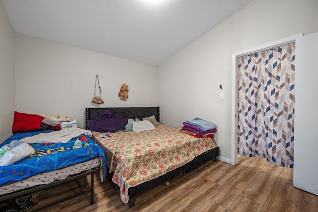 bedroom with lofted ceiling and wood finished floors
