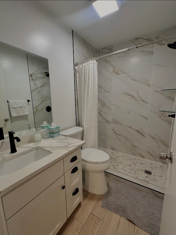 bathroom featuring vanity, a shower stall, toilet, and wood finished floors