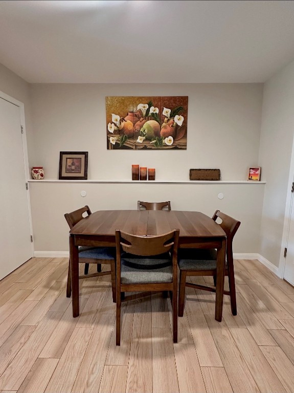 dining space featuring light wood-type flooring and baseboards