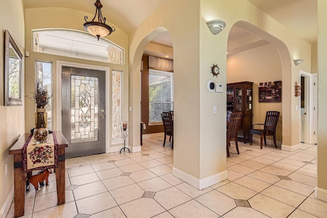 foyer entrance with arched walkways, a wealth of natural light, and light tile patterned flooring