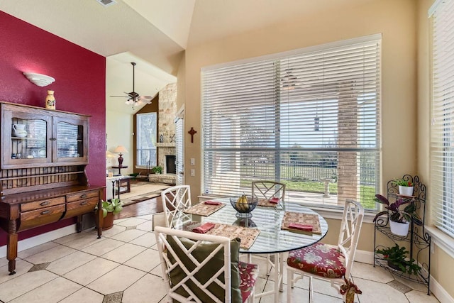 dining space with tile patterned floors, baseboards, a ceiling fan, and vaulted ceiling