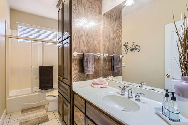 bathroom with tile patterned floors, vanity, toilet, and bath / shower combo with glass door