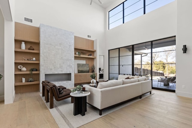 6102 Forest Hills Dr, Austin, TX 78746 - living room with a towering ceiling, light wood finished floors, built in features, and a fireplace