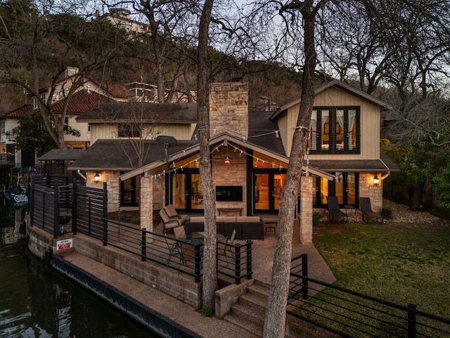 6702 Elfland Dr, Austin, TX 78746 - rear view of house with stone siding, an outdoor living space, a chimney, and roof with shingles