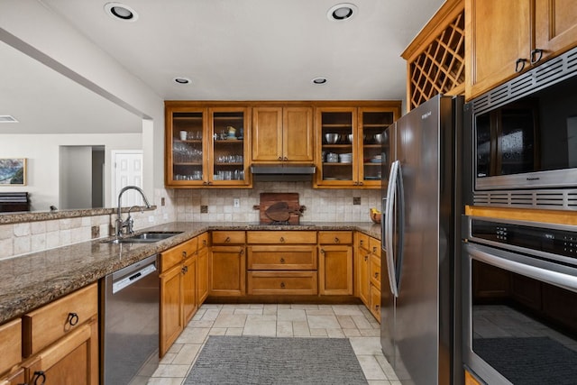 6702 Elfland Dr, Austin, TX 78746 - kitchen with stainless steel appliances, brown cabinets, under cabinet range hood, backsplash, and dark stone counters