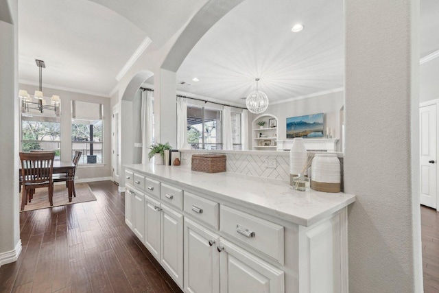 kitchen with dark wood finished floors, an inviting chandelier, and ornamental molding