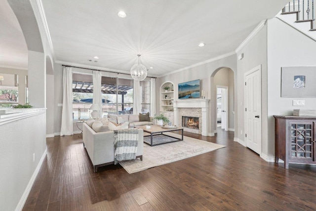living area featuring baseboards, built in shelves, wood-type flooring, and crown molding