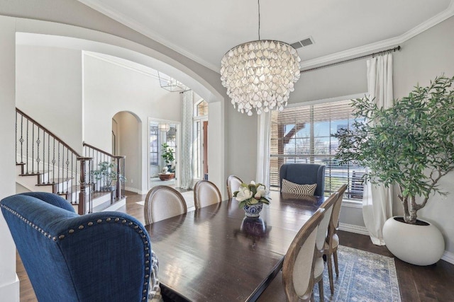 dining space with visible vents, crown molding, a chandelier, wood finished floors, and arched walkways