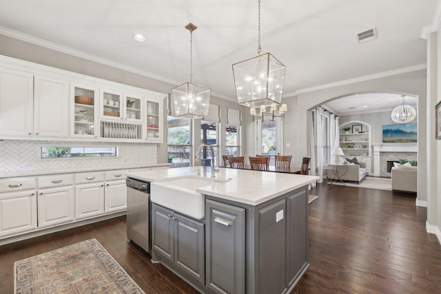 kitchen featuring visible vents, dishwasher, gray cabinets, arched walkways, and a sink