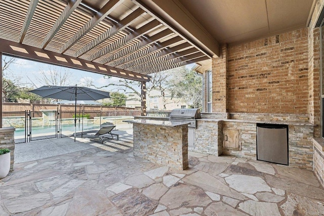 view of patio featuring grilling area, a fenced in pool, a fenced backyard, an outdoor kitchen, and a pergola